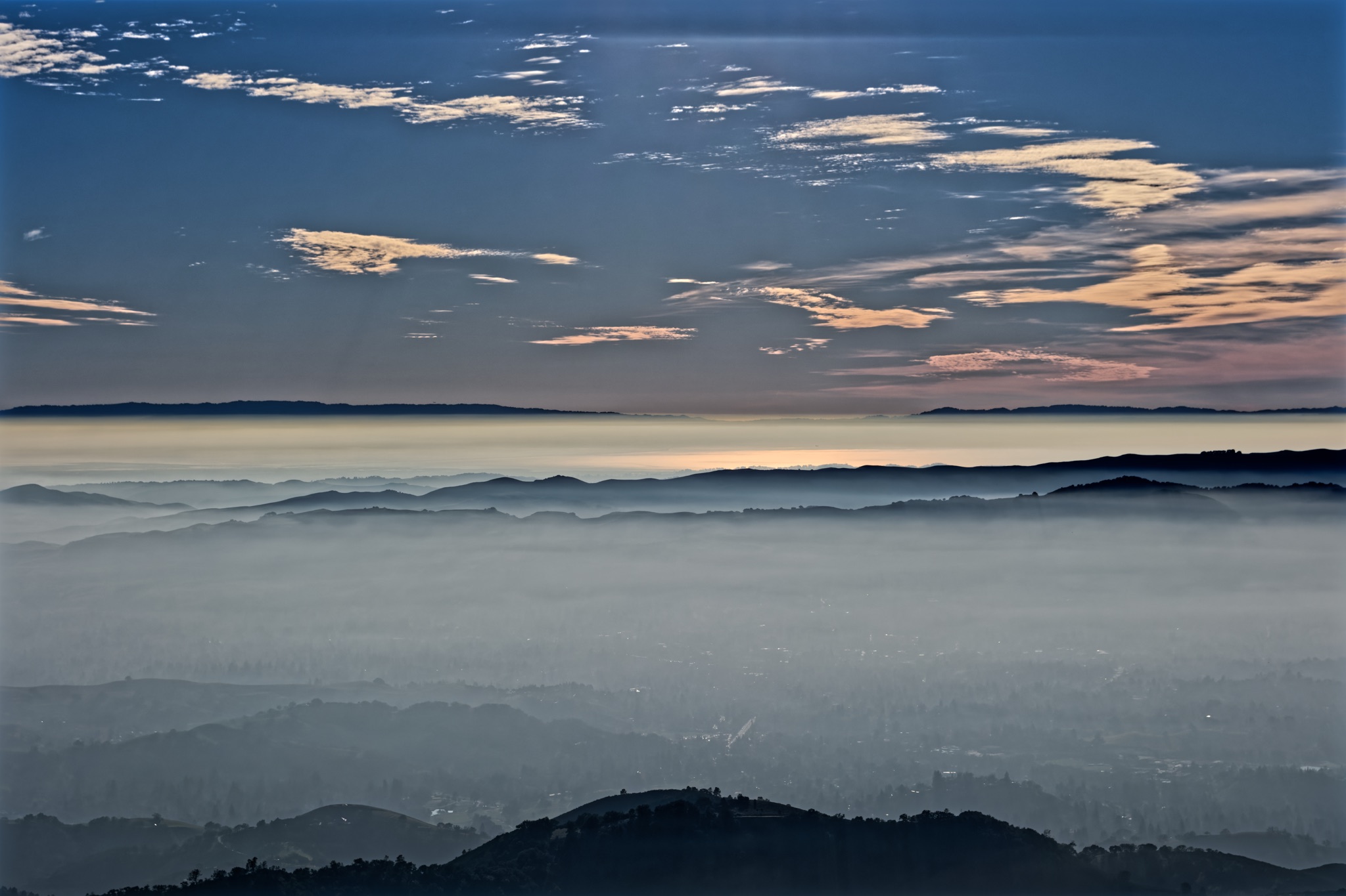 Layered ridges of Mt Diablo rise through a thick sea of fog beneath a twilight sky streaked with pink and blue clouds.