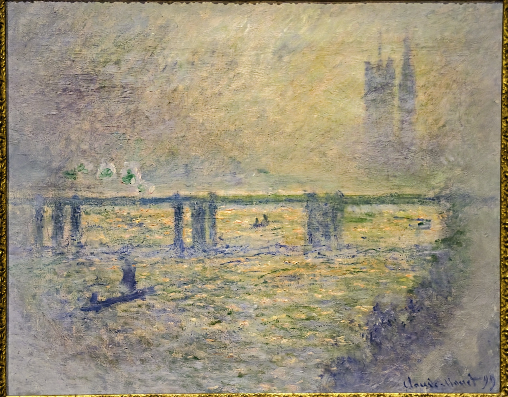 A hazy impressionist painting of a bridge over water with a tall church tower in the distance, framed in gold.