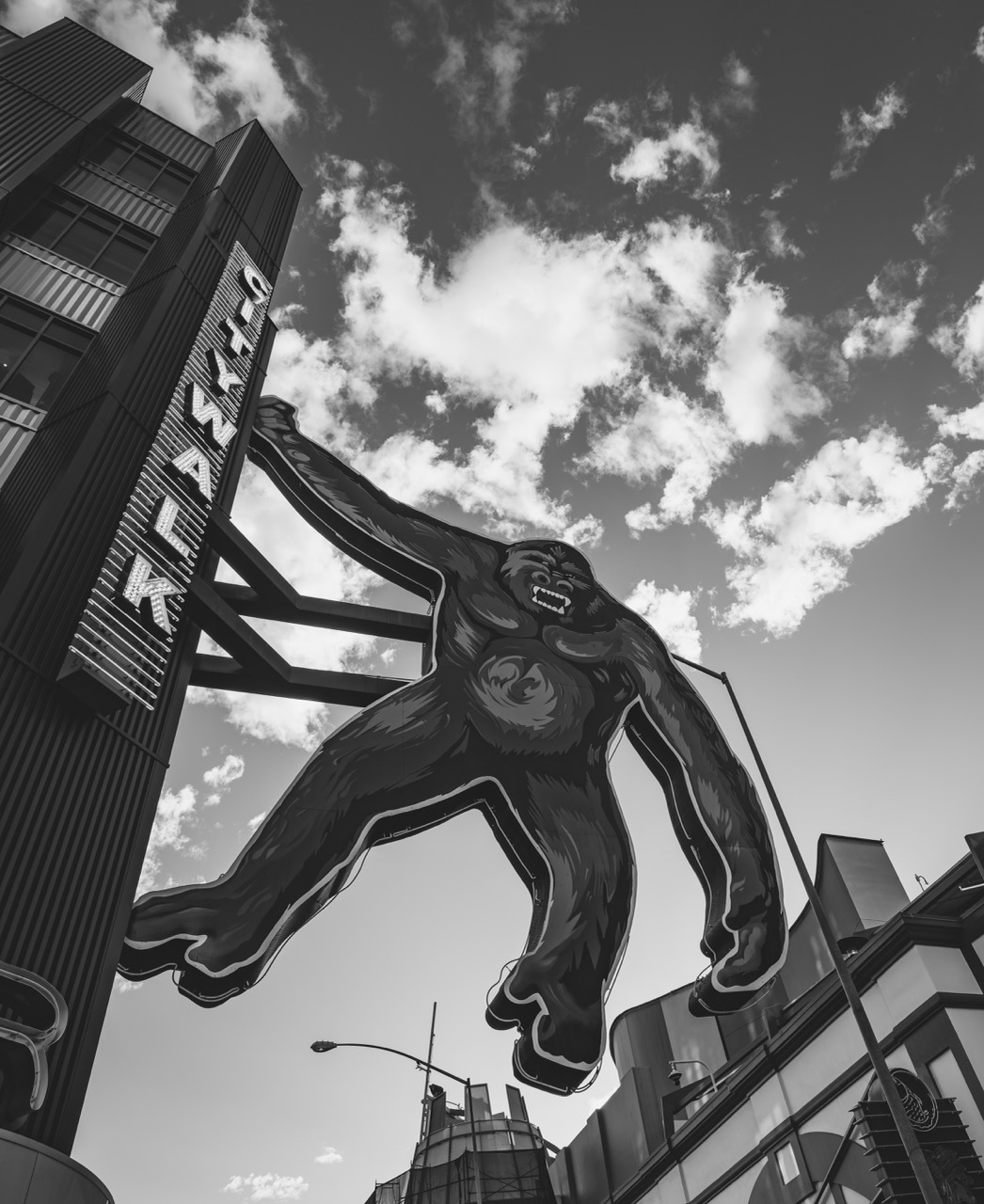 A giant gorilla sign leaps from a building at Universal Citywalk, its mouth open in a roar against a cloudy sky.