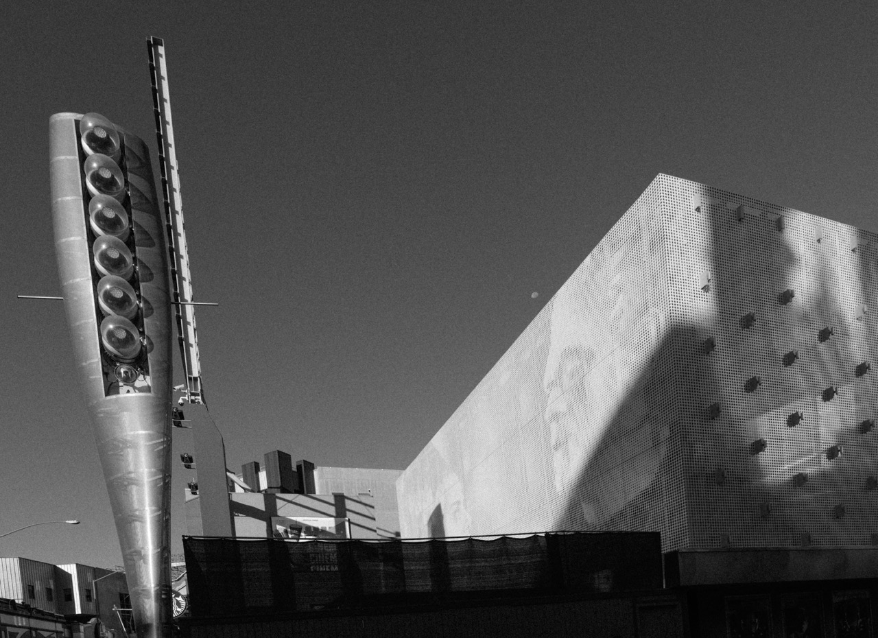 A black and white shot of a tall speaker tower and a perforated metal building facade at Universal Citywalk in California.